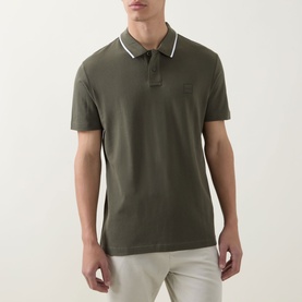 Model wearing Hugo Boss Orange Passerford Tipped Logo Polo Shirt in Bright Green with white tipped collar, styled with light grey trousers.