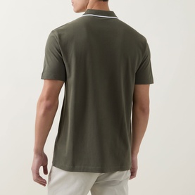 Model wearing Hugo Boss Orange Passerford Tipped Logo Polo Shirt in Bright Green, back view, with white tipped collar detail and light trousers.