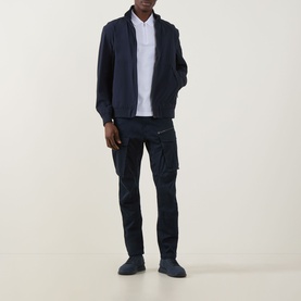 Model wearing Hugo Boss Orange Passertip Logo Polo Shirt in White, styled with navy zip jacket, navy cargo trousers and navy shoes.