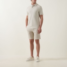 Model wearing Hugo Boss Orange light beige cotton polo shirt, styled with matching chino shorts and white trainers.