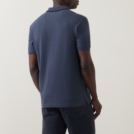 Model wearing Hugo Boss Orange Phoenix Logo Tipped Polo Shirt in dark blue, back view, paired with navy trousers.