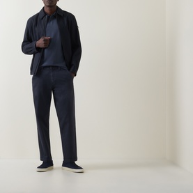Model wearing Hugo Boss Orange Phoenix Logo Tipped Polo Shirt in dark blue, styled with matching navy trousers and dark slip-on shoes.