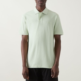 Model wearing Hugo Boss Orange Phoenix Logo Polo Shirt in Open Green, short sleeves, flat knit collar, paired with black trousers.