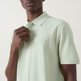 Model wearing Hugo Boss Orange Phoenix Logo Polo Shirt in Open Green, close-up showing flat knit collar and tonal logo detail on chest.