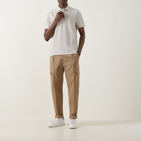 Model wearing Hugo Boss Orange Prime Logo Polo Shirt in Light Beige with cargo trousers and white trainers.
