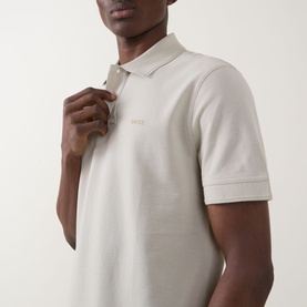 Model wearing Hugo Boss Orange Prime Logo Polo Shirt in light beige, showing polo collar, two-button placket and chest logo detail.