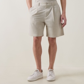 Model wearing Hugo Boss Orange light beige cotton shorts with pleated front and side pockets, styled with white trainers