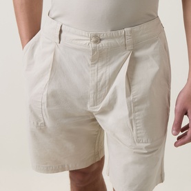 Model wearing Hugo Boss Orange light beige cotton shorts with front pockets and button fastening, styled with a white top.