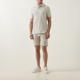 Model wearing Hugo Boss Orange light beige cotton shorts, styled with a matching polo shirt and white trainers.