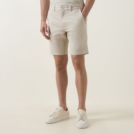 Model wearing Hugo Boss Orange light beige cotton chino shorts, styled with white low-top trainers.