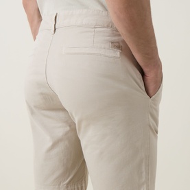 Model wearing Hugo Boss Orange light beige cotton shorts, rear view showing back pocket detail and slim fit silhouette.