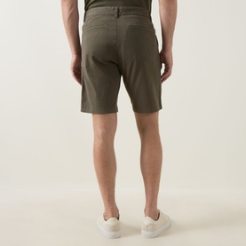 Model wearing Hugo Boss Orange bright green cotton shorts, back view, styled with white trainers.