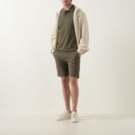 Model wearing Hugo Boss Orange Bright Green cotton shorts, styled with a khaki polo shirt and cream zip-up jacket and white trainers.