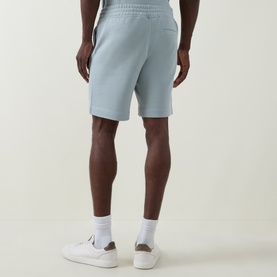 Model wearing Hugo Boss Orange Open Grey cotton sweat shorts, styled with white ankle socks and white trainers, rear view.