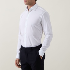 Model wearing Hugo Boss Joe Classic Shirt in white with navy trousers. Kent collar, front placket, long sleeves, curved hem.