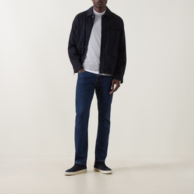 Model wearing Hugo Boss Orange Delaware Slim Fit Jeans in 412 Navy, styled with a dark jacket, grey T-shirt, and navy trainers.
