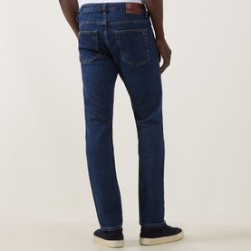 Model wearing Hugo Boss Orange Delaware Slim Fit Jeans in navy, rear view showing patch pockets and belt loops, styled with navy trainers.