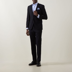 Model wearing Hugo Boss Hank Performance-Stretch Shirt in light pastel blue, styled with a navy suit, dark trousers and black dress shoes.