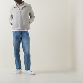 Model wearing Hugo Boss Orange straight jeans in turquoise/aqua, styled with a light grey zip jacket and white trainers.