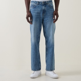 Model wearing Hugo Boss Orange straight-leg jeans in turquoise/aqua washed denim, styled with white trainers