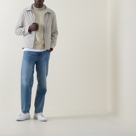Model wearing Hugo Boss Orange straight jeans in turquoise/aqua, styled with a light grey zip jacket, cream top and white trainers.