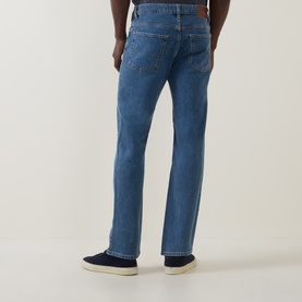 Model wearing Hugo Boss Orange 3049 straight jeans in bright blue, rear view, styled with navy trainers.
