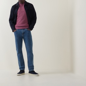 Model wearing Hugo Boss Orange Bright Blue straight jeans, styled with a pink jumper, navy harrington jacket and navy trainers.