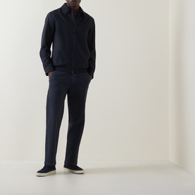 Model wearing Hugo Boss Orange dark blue straight jeans with navy zip-up jacket and cream slip-on shoes.