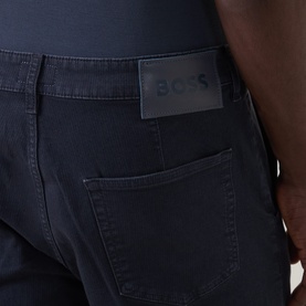 Model wearing Hugo Boss Orange dark blue straight jeans, close-up of back pocket with tonal logo patch detail.