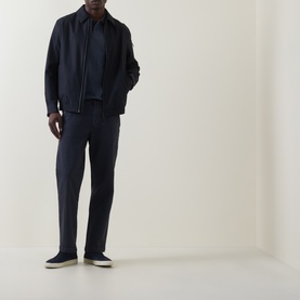 Model wearing Hugo Boss Orange dark blue straight-fit jeans with a navy bomber jacket and navy polo shirt, styled with white-soled trainers.