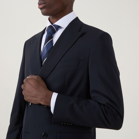 Model wearing Hugo Boss Houston Double-Breasted Suit Jacket in dark blue with peak lapels, styled with white shirt and navy striped tie.