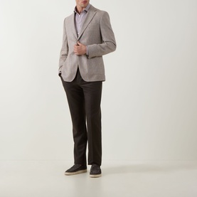Model wearing Hugo Boss Hutson Medium Beige single-breasted suit jacket with notched lapels, styled with dark trousers and navy trainers.