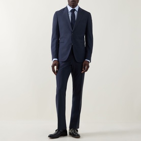 Model wearing Hugo Boss Huge Two-Piece Suit in dark blue wool, styled with a light blue shirt and tie, and black leather shoes.