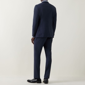 Model wearing Hugo Boss Huge Two-Piece Suit in dark blue, rear view, styled with a white shirt and black leather shoes.
