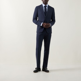 Model wearing Hugo Boss Huge Two-Piece Suit in dark blue, styled with a light blue shirt, navy tie and black leather shoes.