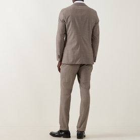 Model wearing Hugo Boss Huge Single-Breasted Two-Piece Suit in dark beige wool, rear view, styled with black dress shoes.