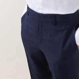 Model wearing Hugo Boss dark blue tailored trousers in wool-linen blend, styled with a white shirt, close-up of waist and hip detail.