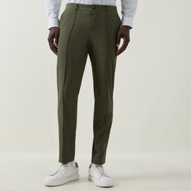 Model wearing Hugo Boss Open Green slim-fit trousers with pressed front crease, styled with a white shirt and white trainers.