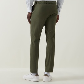 Model wearing Hugo Boss Open Green slim-fit trousers, styled with a white shirt and white trainers, rear view.