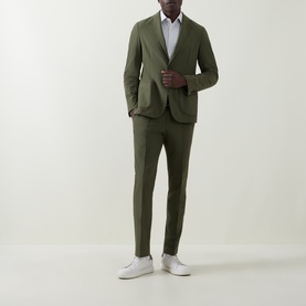 Model wearing Hugo Boss Open Green slim-fit trousers, styled with matching green blazer and white shirt and trainers.