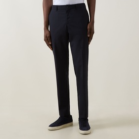 Model wearing Hugo Boss dark blue slim-fit trousers in wool blend, styled with white trainers and a tucked-in white shirt.