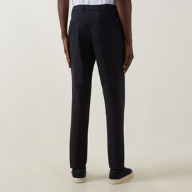 Model wearing Hugo Boss dark blue slim-fit trousers in virgin wool blend, rear view, styled with cream loafers.