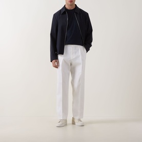 Model wearing Hugo Boss Open White cotton trousers, styled with navy zip-up jacket and white trainers.
