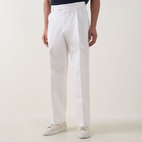Model wearing Hugo Boss open white cotton trousers with pleat front detail, styled with white trainers and navy top.