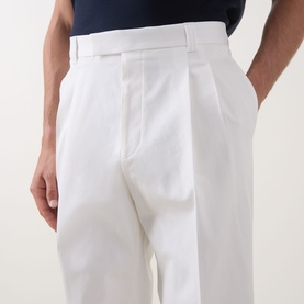 Model wearing Hugo Boss Open White cotton trousers with front pleats, belt loops, and side pockets, styled with a navy top.