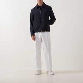 Model wearing Hugo Boss Open White cotton trousers, styled with a navy zip-up jacket and white trainers.