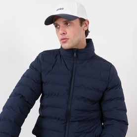 Model with Hugo Jake-OX-N Logo Baseball Cap in Natural white, six-panel construction with contrasting peak visor, styled with navy puffer jacket.