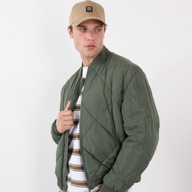 Model with Hugo Jake-ME Stacked Logo Baseball Cap in beige, styled with an olive quilted bomber jacket and striped top.