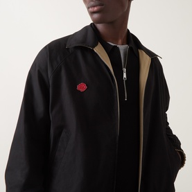 Model wearing Hugo casual jacket in medium beige, shown in black with zip fastening and red rose embroidered badge, beige lining visible at collar