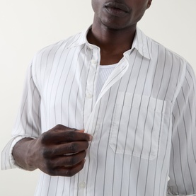 Model wearing Hugo Erillo Striped Shirt in Natural, white with vertical stripes, point collar, chest pocket, over a white vest.